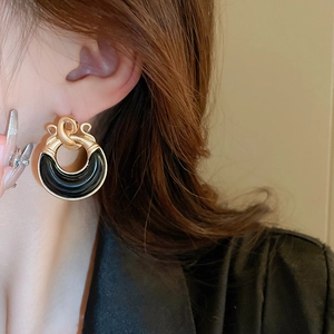 Close-up of model wearing vintage gold and black resin geometric knot earrings