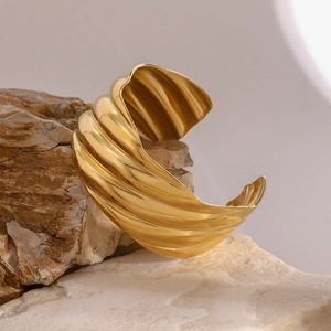 Polished 18k gold plated stainless steel chunky open croissant cuff bangle on rock