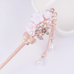 Detail of golden floral hair stick with white flowers, hanging pearls and tassel