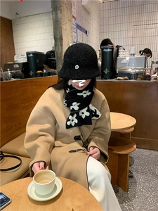 Detail of warm black and white floral knitted scarf with cozy teddy bucket hat