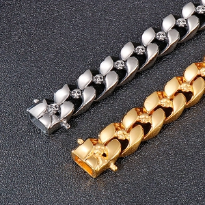 Macro detail of silver and gold Cuban link bracelets featuring 3D skull relief patterns
