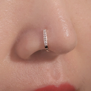 Close-up of a rose gold nose ring with sparkling diamonds on a model's nose