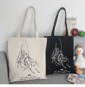 Detail of artistic cat graffiti and typography on beige and black canvas tote bags