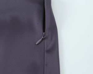 Détail de la fermeture éclair invisible sur le tissu en satin de soie violet foncé