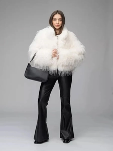 Full body view of white faux fur coat paired with black flared pants and handbag