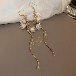 Détail de boucles d'oreilles muguet avec perles, cristaux et longues franges dorées