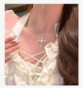 Close-up of starburst cross pendant with zircon stones on silver-tone chain