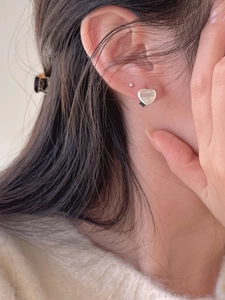Close-up of shell heart hoop earrings showing the elegant worn look on the earlobe