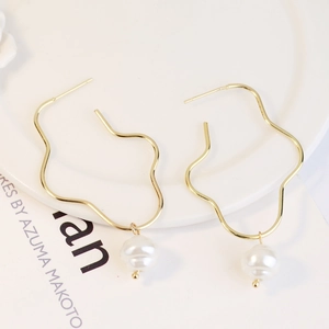 Detailed macro view of gold irregular wave drop earrings featuring elegant white pearls