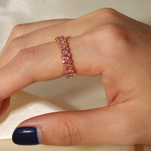Detail of pink oval gemstones set in a gold-plated open ring on a satin background