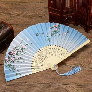 Detail of silk folding fan featuring pink plum blossoms, carved bamboo, and blue tassel
