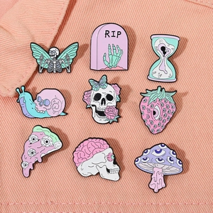Macro view of pastel pink and green enamel pins featuring skull mushrooms and strawberries