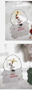 Detail of metal Merry Christmas sign with snowman figurine and dried flower accents