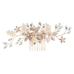 Detail of bridal hair comb featuring golden flowers, pearls, and crystals on a white background