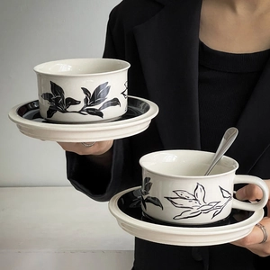 Detail of vintage hand-painted floral ceramic coffee cup and saucer set held by hand