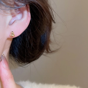Détail macro de boucles d'oreilles gourde dorées élégantes portées sur l'oreille