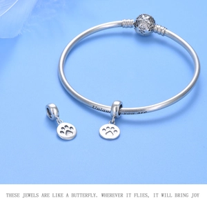 Macro view of sterling silver bracelet with paw pendants and Unique as you are engraving