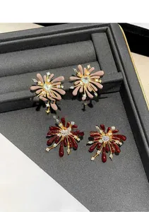 Close-up of floral fireworks stud earrings with red enamel and heart-shaped zircon stones