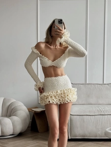 Detail of off-white two-piece set featuring 3D popcorn texture and ruffled hemlines