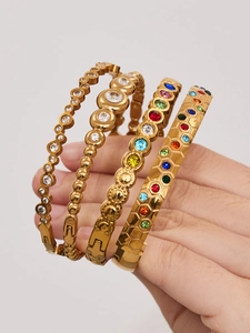 Detailed close-up of four gold stainless steel bangles with colorful zircon inlays