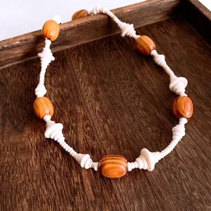Vintage bohemian necklace with oval wooden beads and white accents on wooden tray
