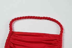 Detail of red dress with braided halter straps and pleated bodice craftsmanship