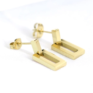 Detailed macro view of 18K gold rectangular earrings with a brushed metal texture finish