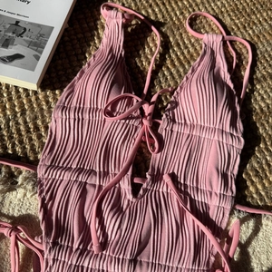 Dettaglio del costume intero rosa testurizzato con coulisse e finitura in tessuto arricciato
