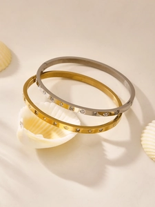 Detail of gold and silver stainless steel bangles with star engravings and cubic zirconia