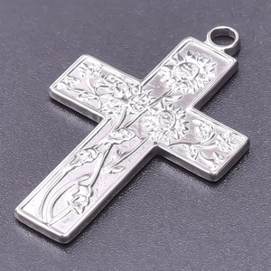 Macro shot of 18k gold plated stainless steel cross pendant with floral engraving