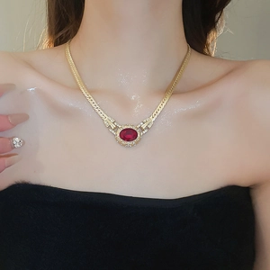 Detail of vintage gold flat snake chain necklace with red oval gemstone pendant