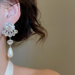 Close-up of vintage silver flower earrings with crystals and a white teardrop pearl
