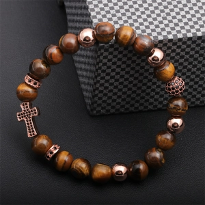 Detail of tiger eye beads with rose gold cross charm on a luxury leather surface