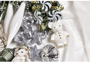 Dettaglio ravvicinato di ornamenti natalizi argento e verdi in varie forme festive