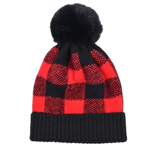 Texture détaillée du bonnet en maille à carreaux rouge et noir avec pompon en fausse fourrure