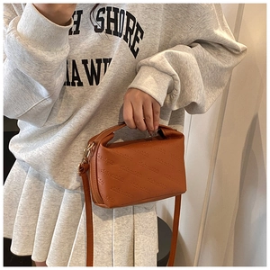 Close-up of caramel brown handbag featuring rich rabbit embossed pattern and gold hardware
