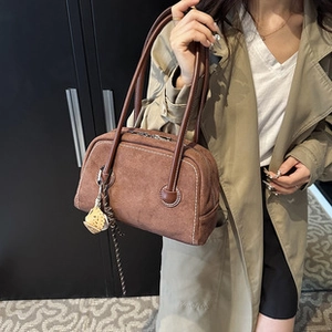 Brown faux suede tote bag with white stitching detail and slender straps shown on a model