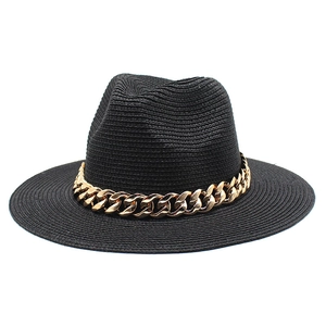 Detail of black straw fedora hat featuring a chunky gold acrylic chain decorative band