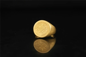 Macro detail of gold compass star signet ring with engraved Lucleon branding on side
