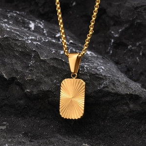 Macro shot of gold rectangle pendant with sunburst texture on black rock background