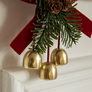 Christmas hanging ornament with three gold bells, red velvet bow and green pine cones