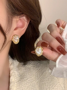 Detailed close-up of French vintage irregular pearl earrings with gold metallic edges