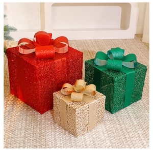 Detailed view of three stackable Christmas gift boxes with bows in red, gold, and green