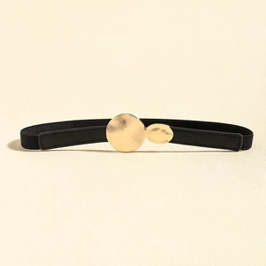 Detail of elegant gold double-circle sunburst buckle on black elastic skinny belt