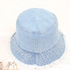 Detailed view of frayed edges on a light blue denim bucket hat with fringe texture