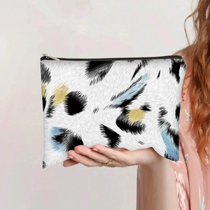 Close-up of leopard print canvas bag with silver zipper held in hand by a model
