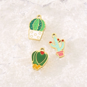 Detail of colorful enamel cactus pendants in gold plating on white icy texture