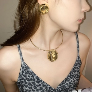 Close-up of golden oval heart earrings and choker necklace set on a female model