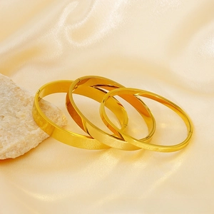 Detail of three 18K gold-plated stainless steel bangles set on premium champagne silk