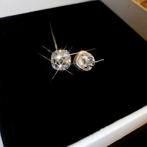 Detail showing square-cut crystal earrings with silver claws on black velvet background